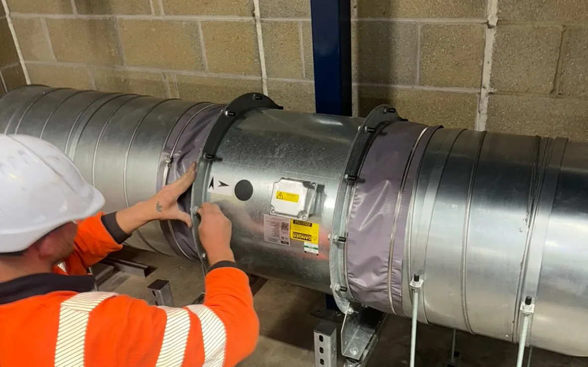 A Castle engineer in full PPE working on ductwork on site